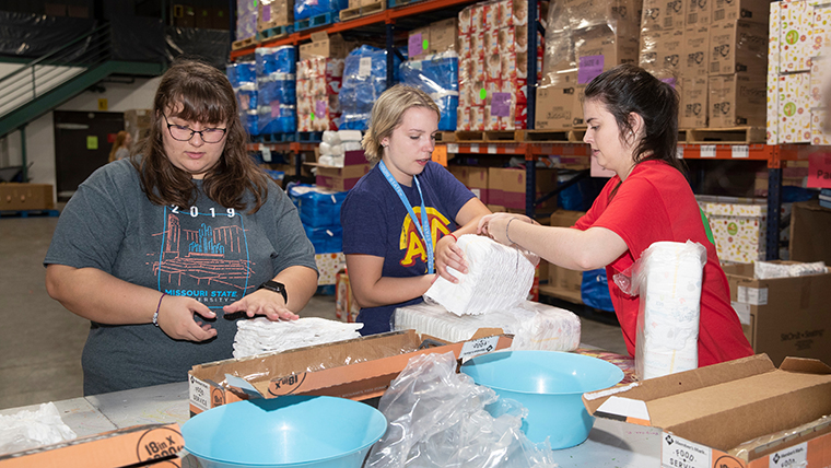 three students working at a food distribution center
