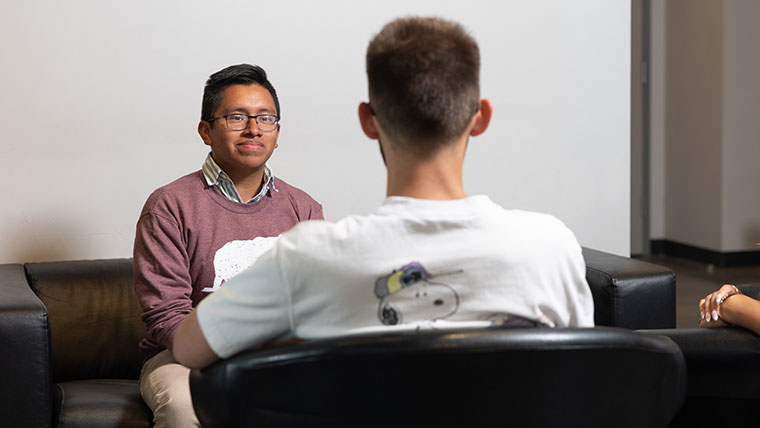An admissions counselor pays attention as his student chats with him.
