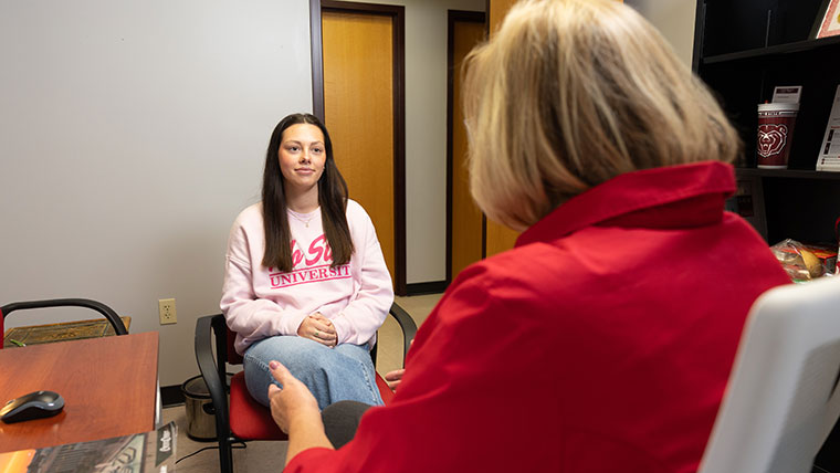 A student listens intently during a meeting with her academic advisor.