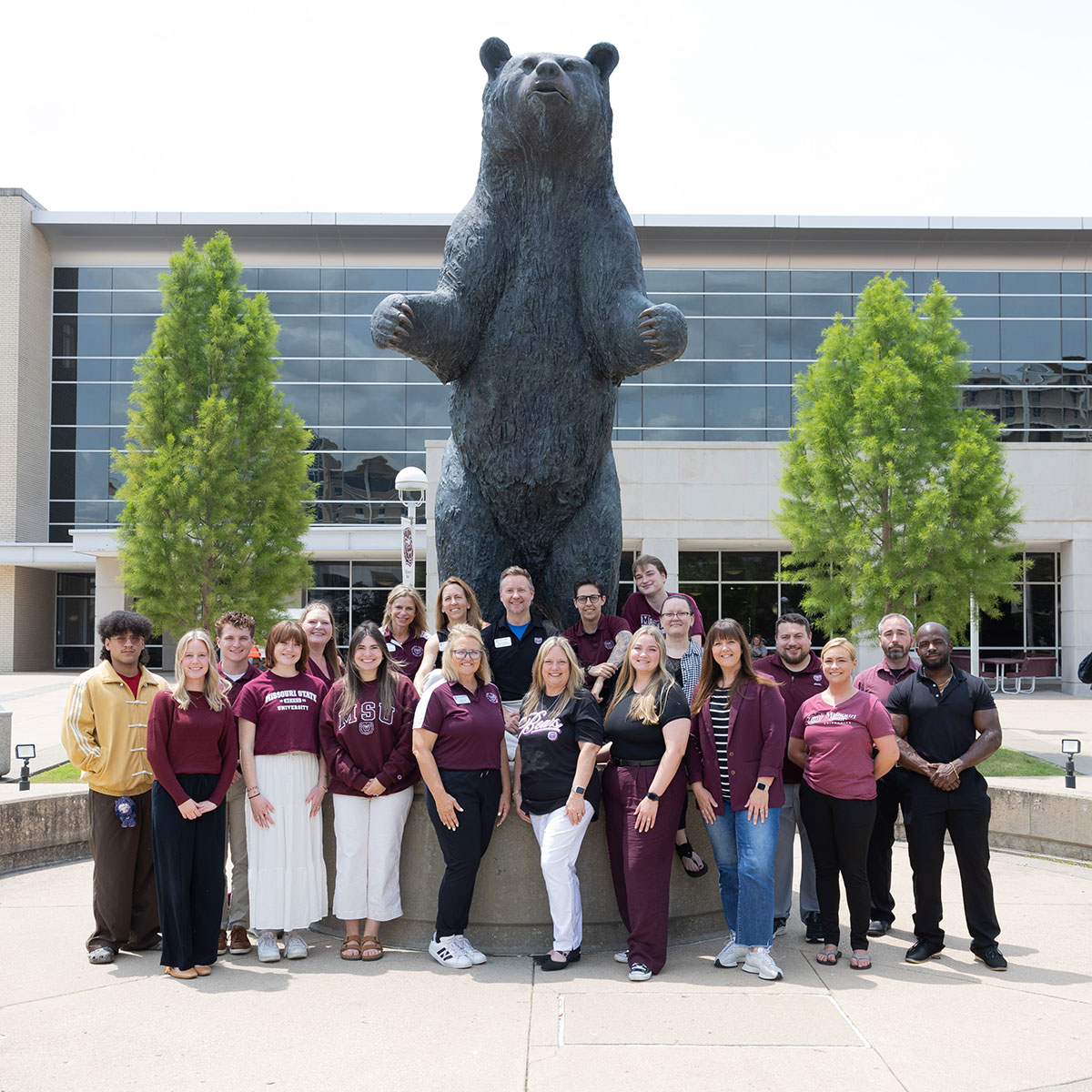 Wellness staff and administration from Magers Health and Wellness, the Counseling Center and Foster Recreation Center gather around the bear statue in front of the Plaster Student Union.