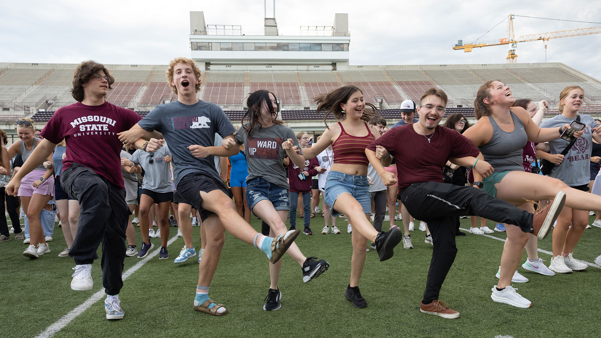 Six Missouri State students energetically perform a kickline dance at Plaster Stadium.